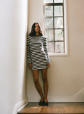 Woman in a striped mini dress standing in a room with a window.