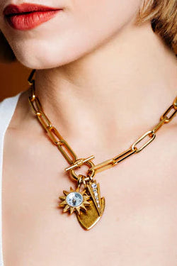 Gold chain necklace with a heart-shaped pendant worn by a person.