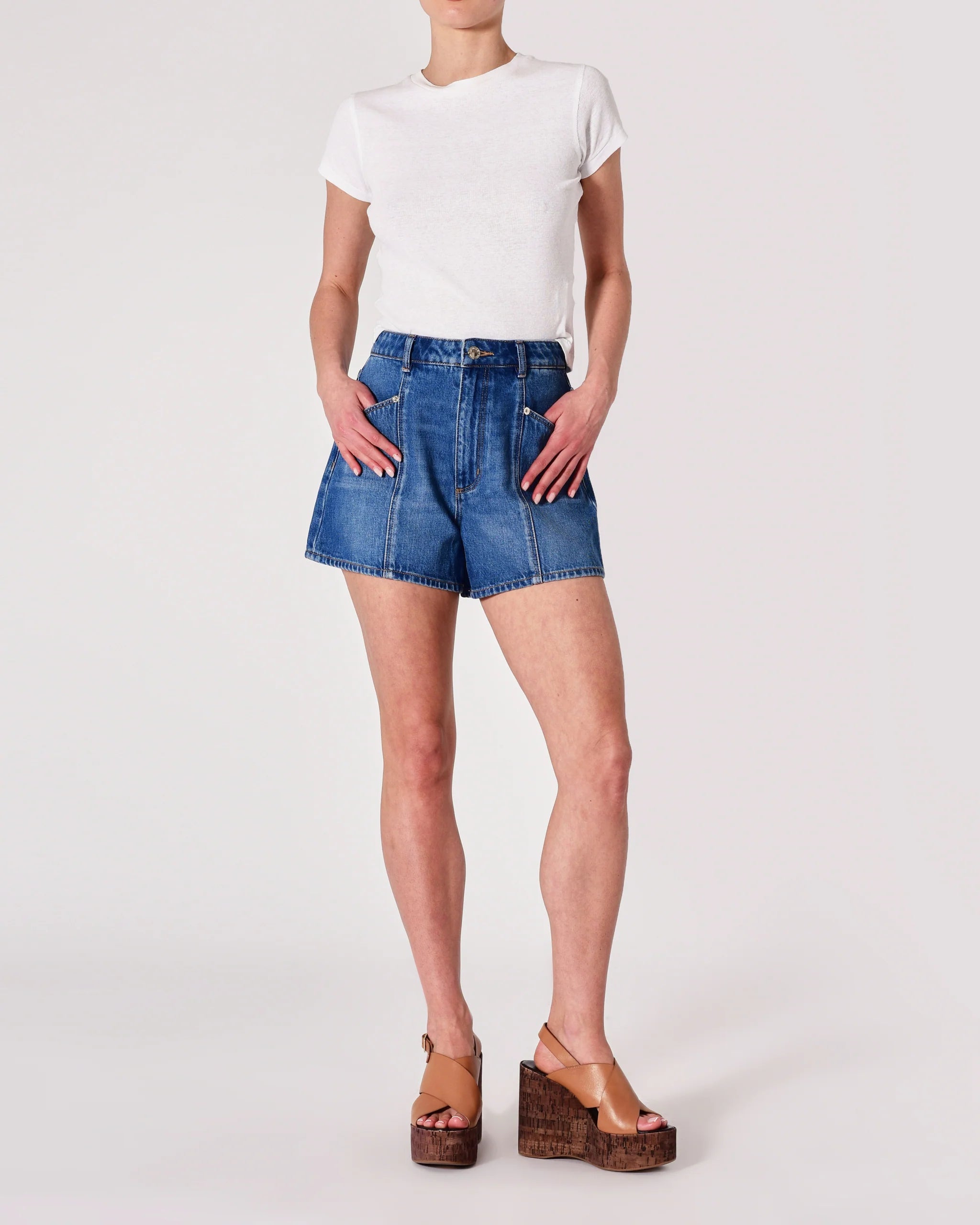Person wearing blue denim shorts and a white t-shirt on a plain background