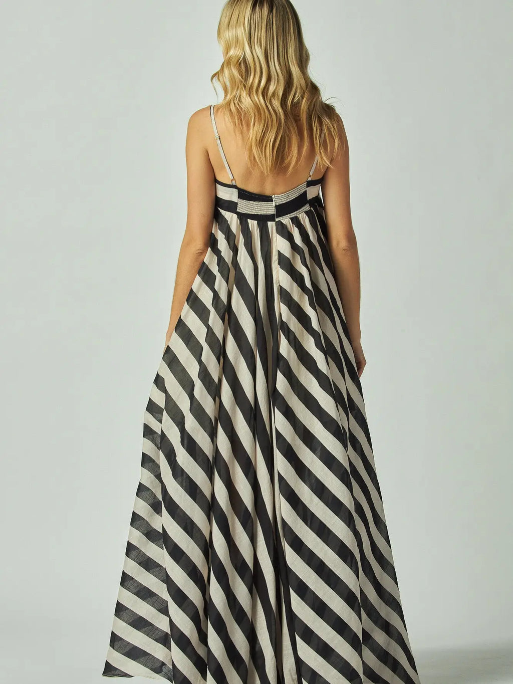 Woman wearing a black and white striped dress against a plain background