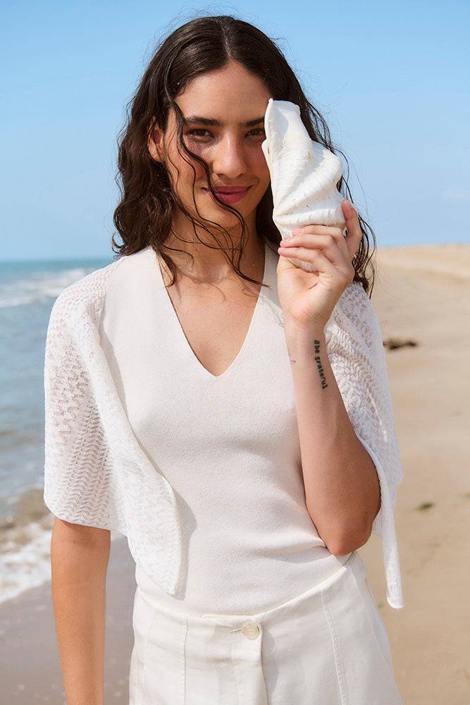 Woman holding a white seashell on a beach