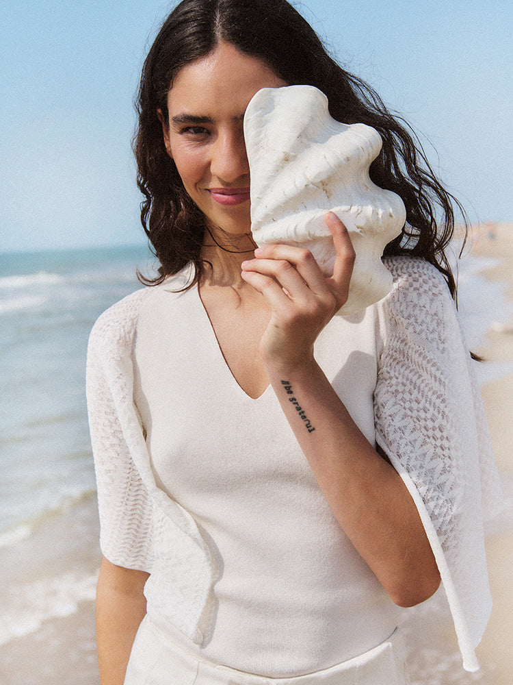 Woman holding a large shell on a beach