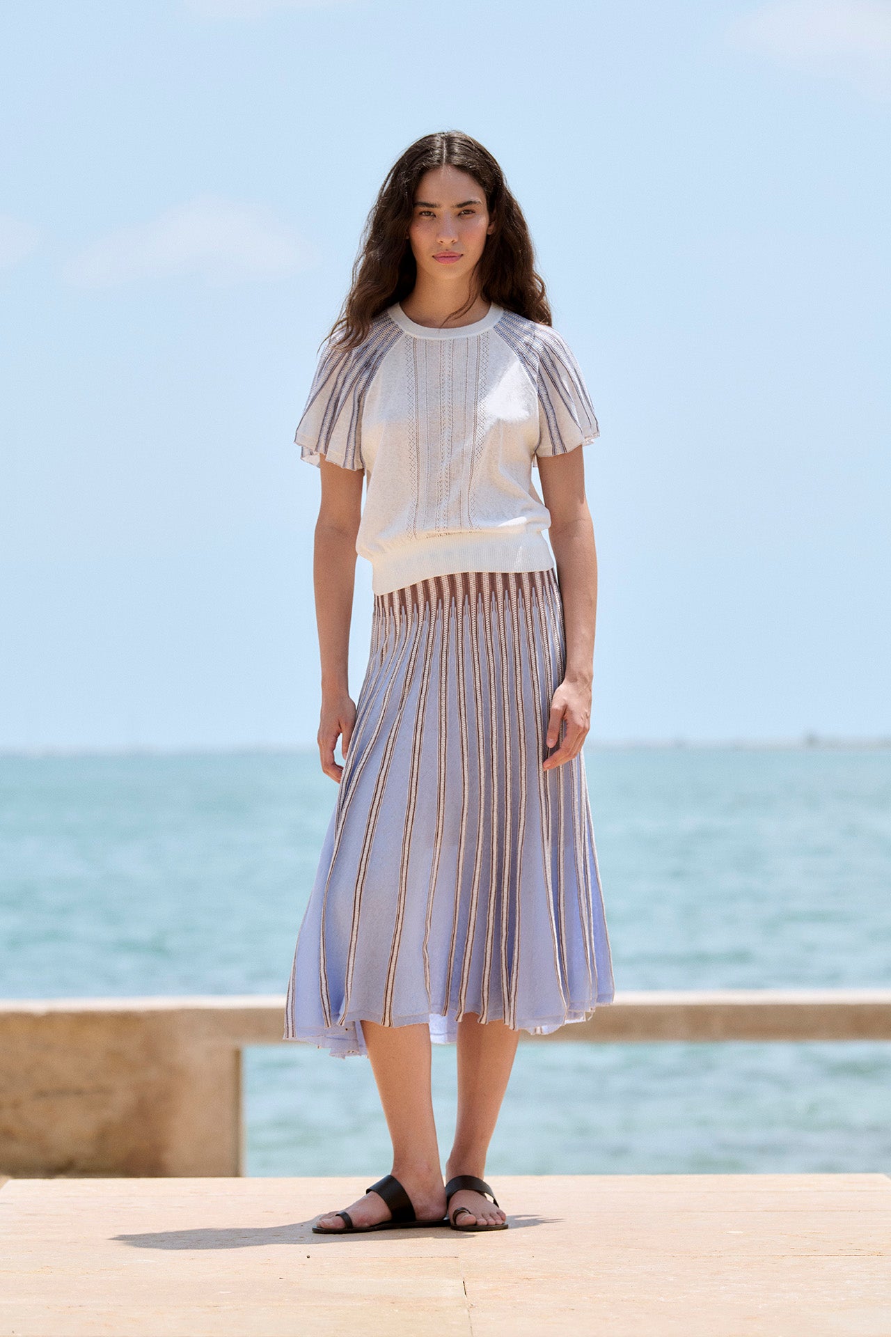 Woman wearing a sita murt striped matching set dress standing by the ocean