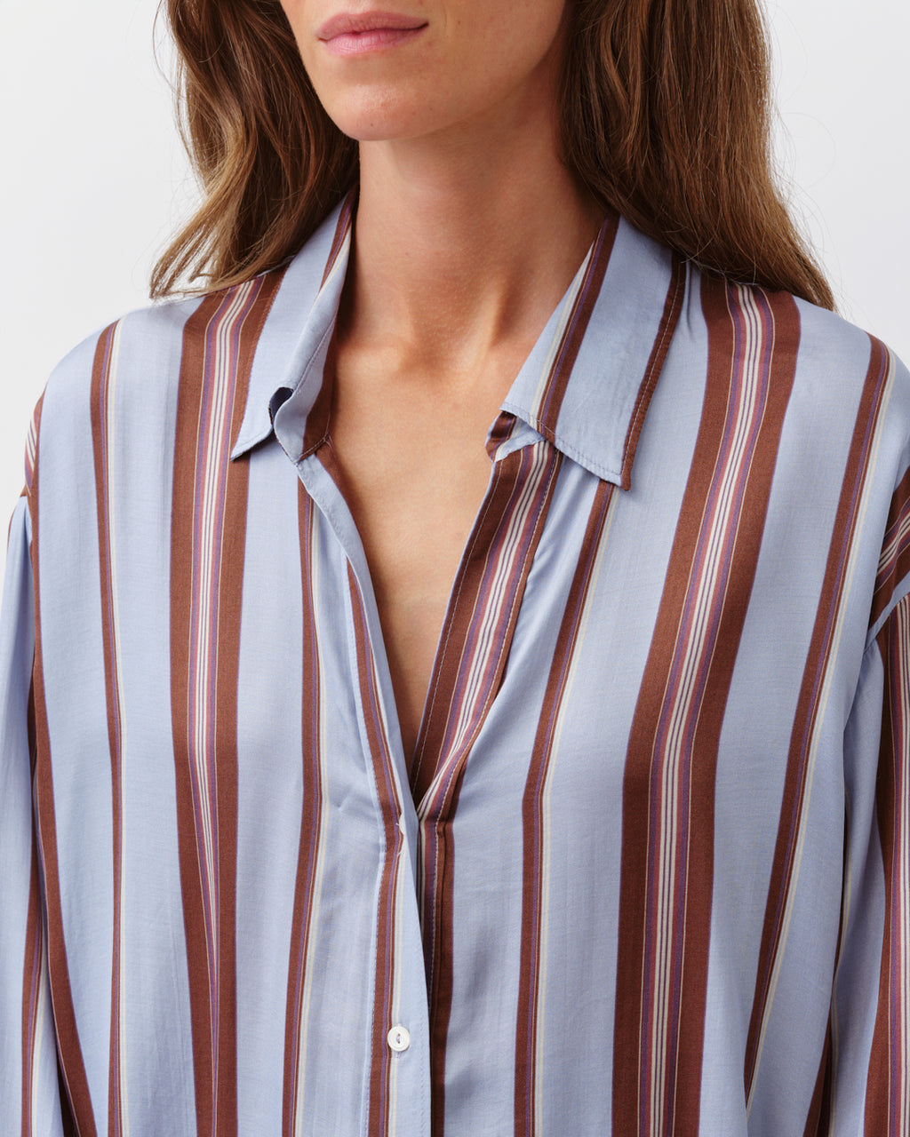 Close-up of a person wearing a striped shirt with vertical brown and white stripes.