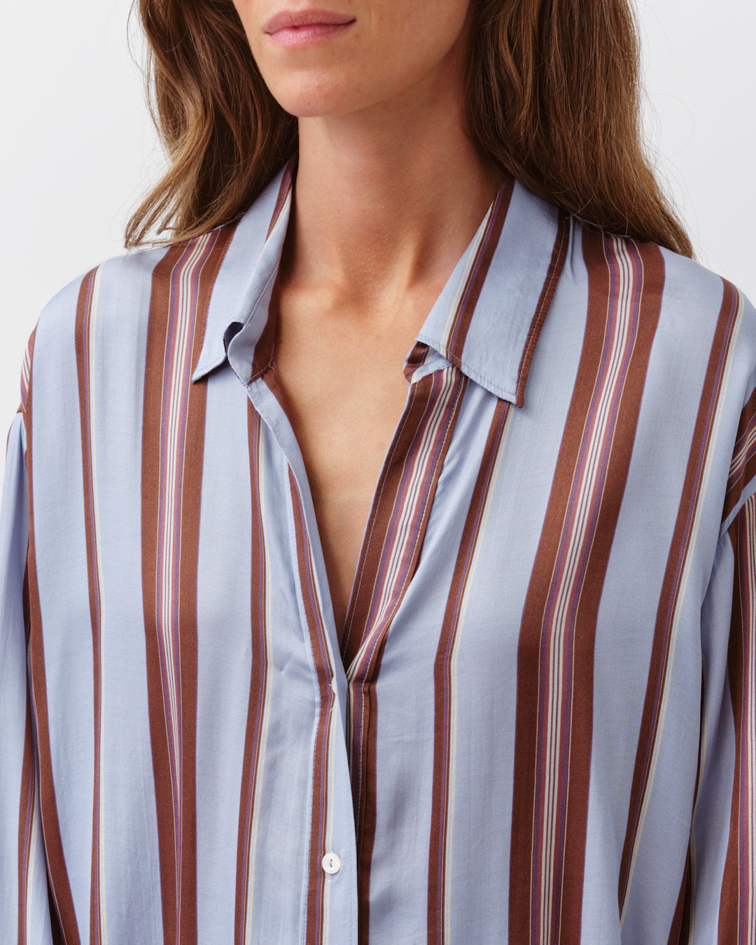 Close-up of a person wearing a striped shirt with vertical brown and white stripes.