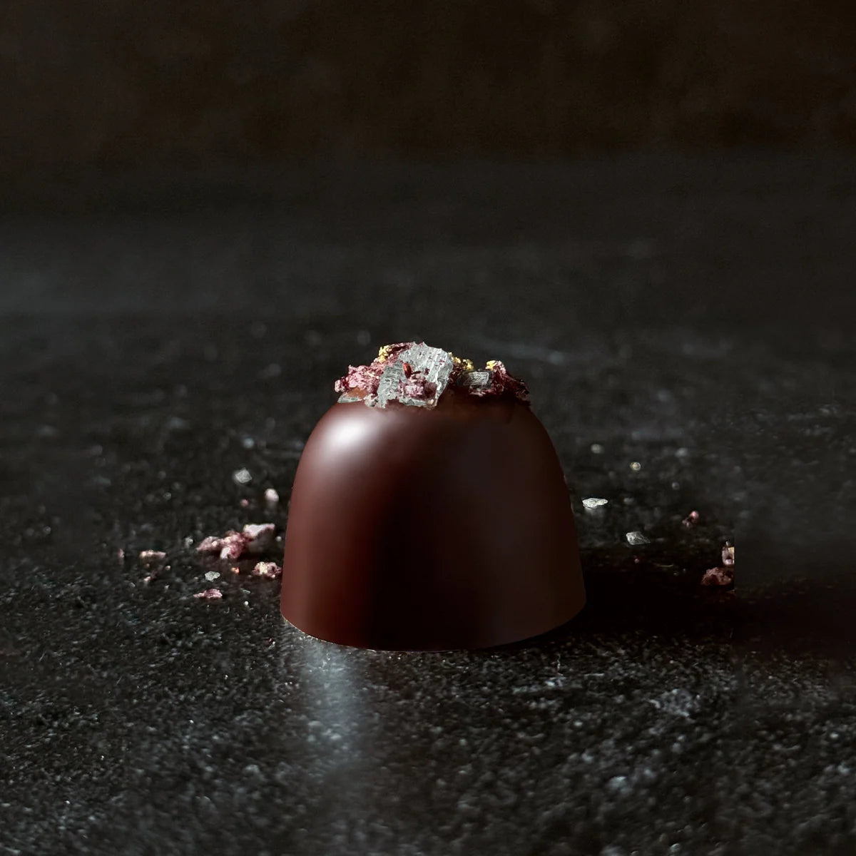 Chocolate truffle with decorative elements on a dark surface