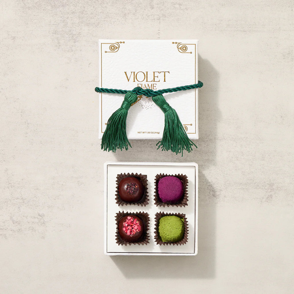 Box of colorful truffles with a green tassel on a beige background