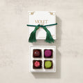 Box of colorful truffles with a green tassel on a beige background