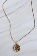 Gold necklace with a pendant on a white marble surface