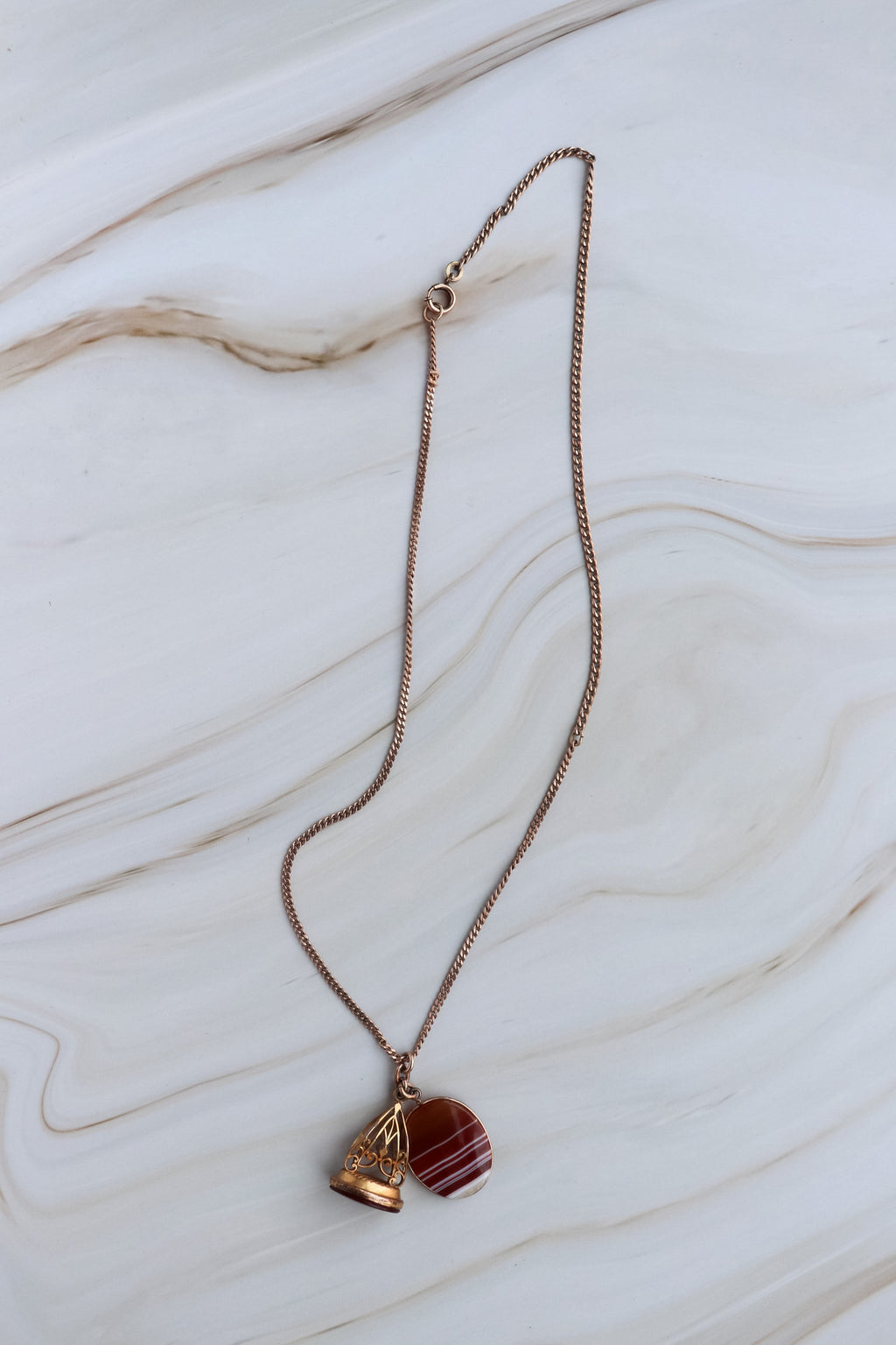 Necklace with a heart-shaped pendant and red stone on a marble surface