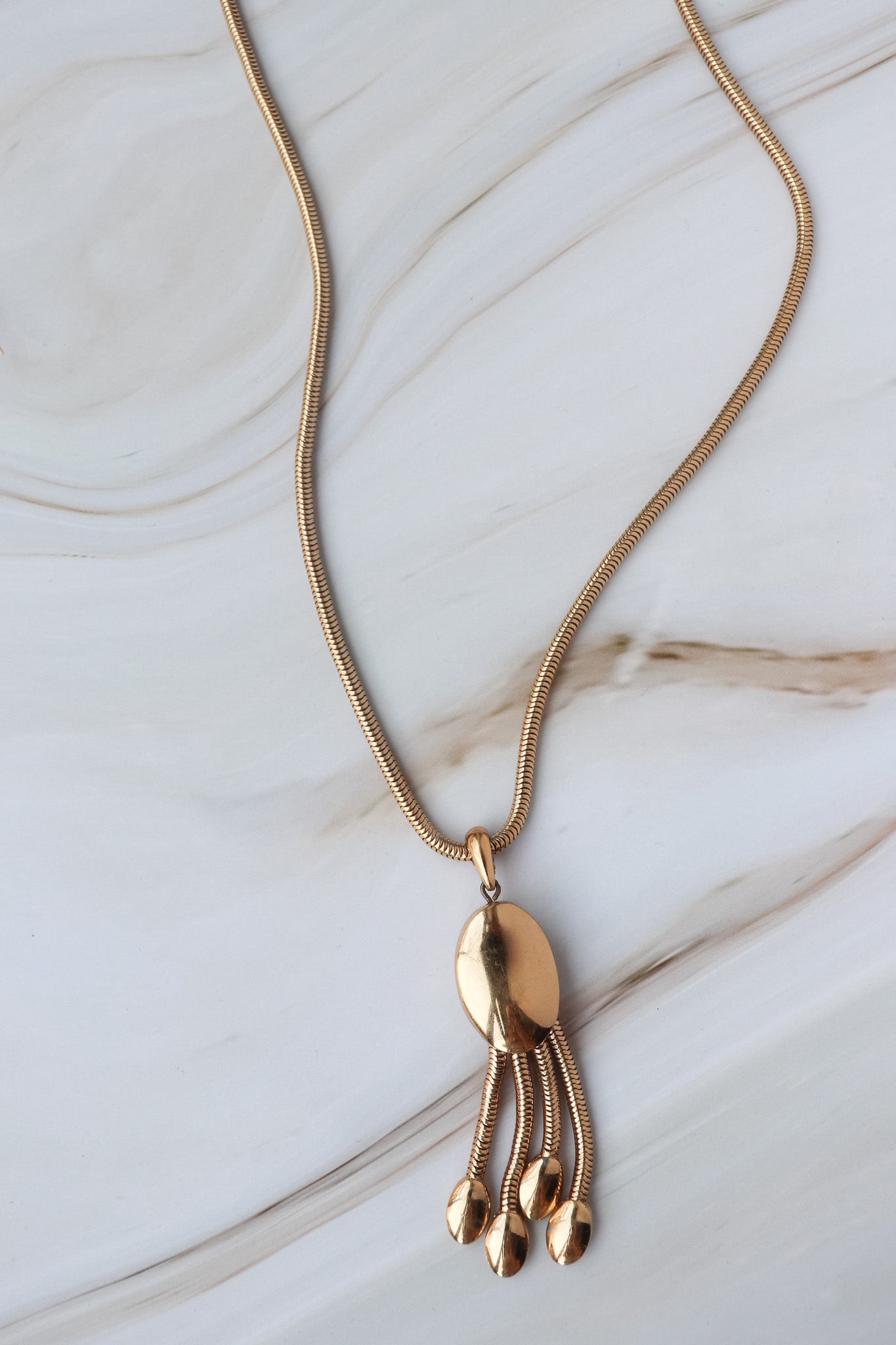 Gold necklace with a pendant on a marble surface