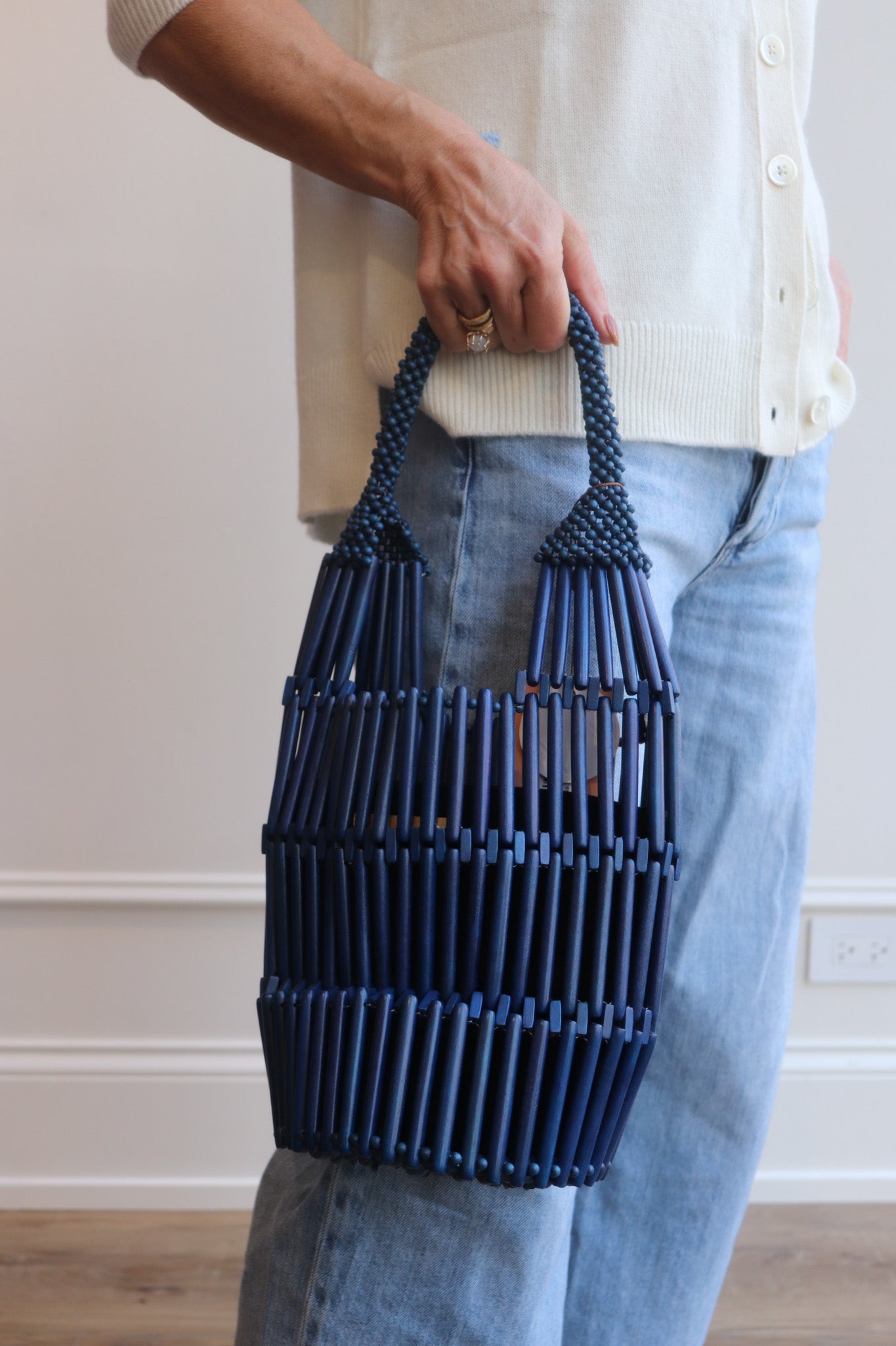 Person holding a handmade blue beaded bucket bag with a neutral background