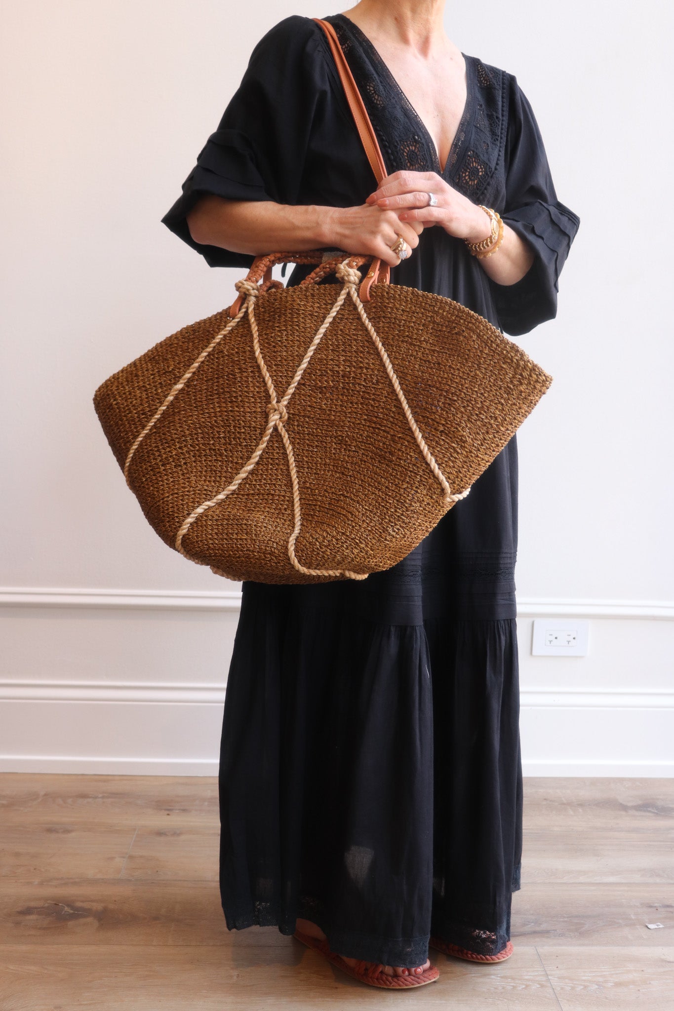 Person holding a brown woven bag against a plain background