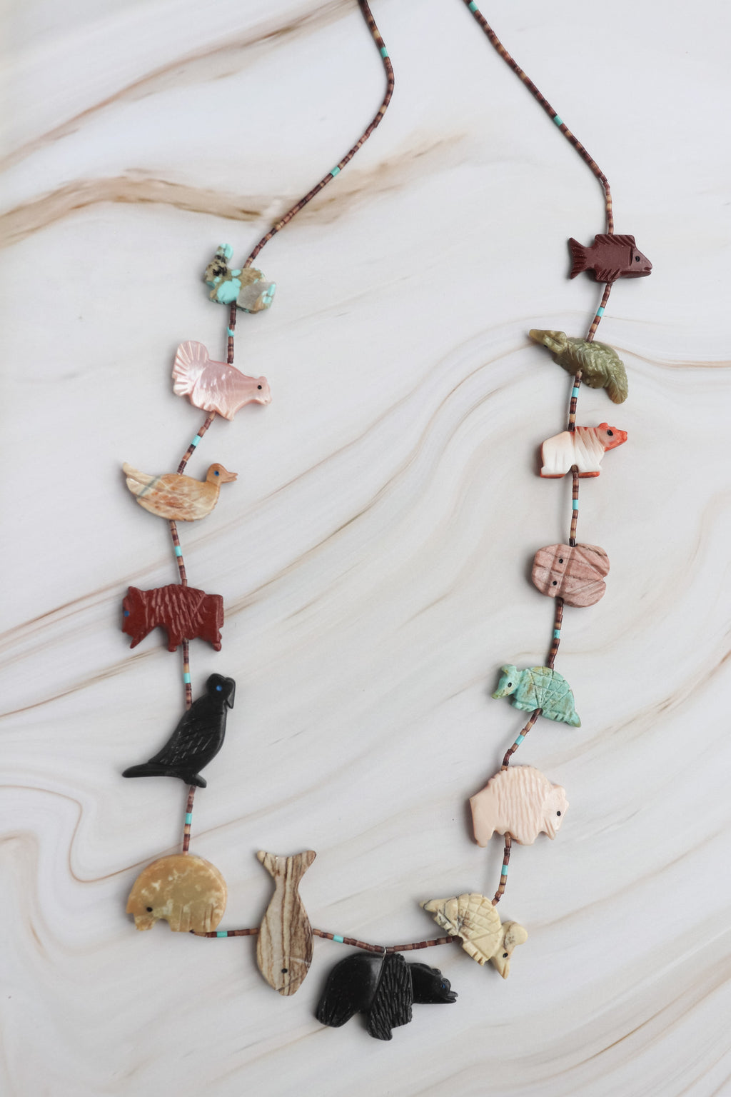 fetish Necklace with various animal-shaped beads on a marble surface