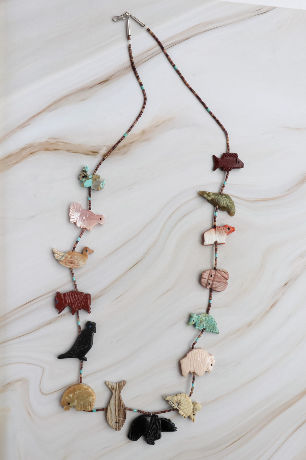 vintage fetish animal Necklace with animal-shaped pendants on a marble surface