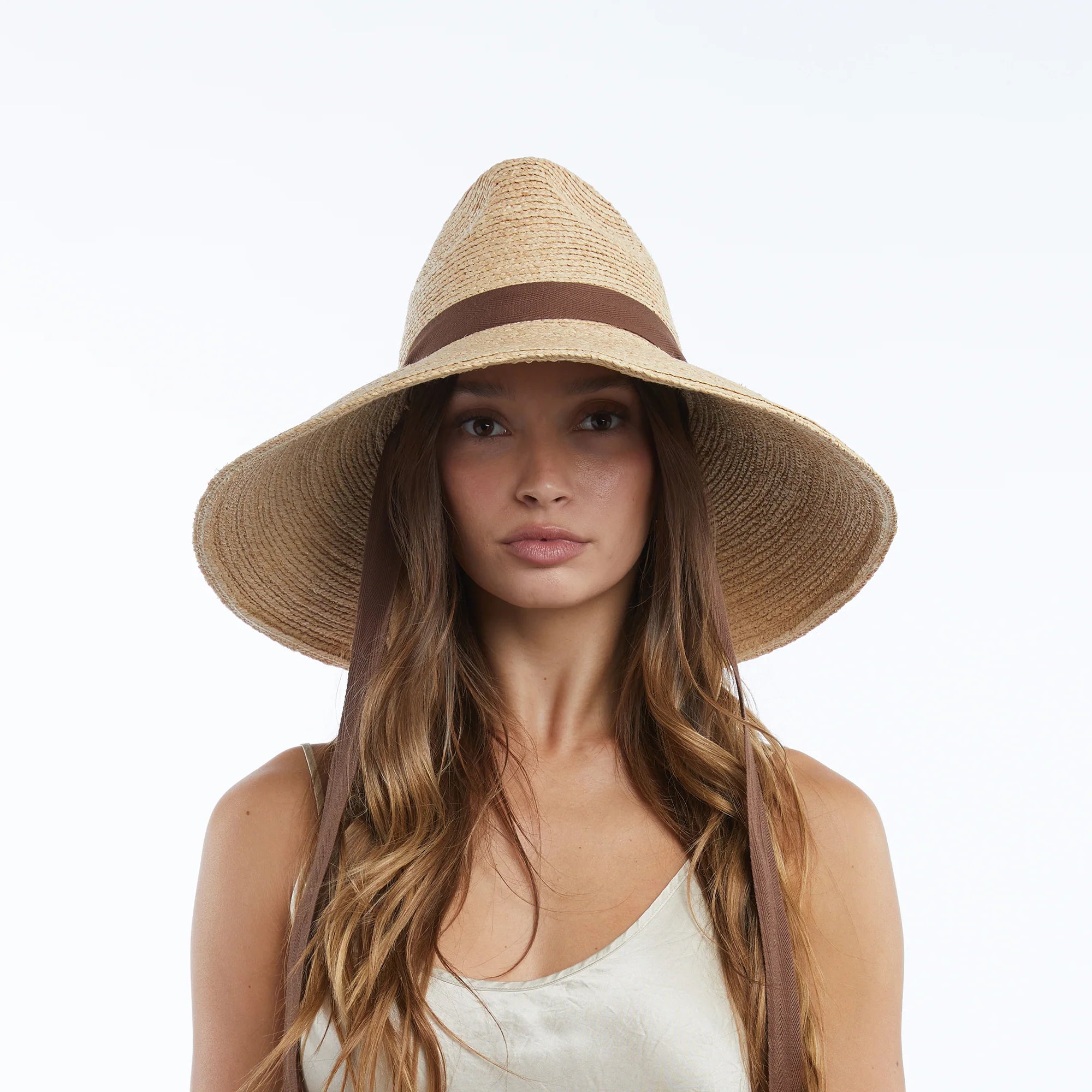 Woman wearing a straw hat with a brown band on a white background