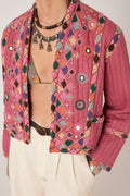 Person wearing a colorful embroidered pink jacket with geometric patterns.