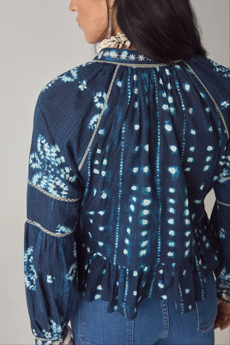 Navy blue and white patterned blouse with long sleeves on a plain background