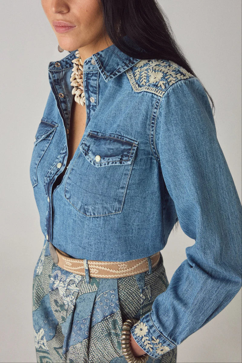 Denim jacket with intricate embroidery on a plain background