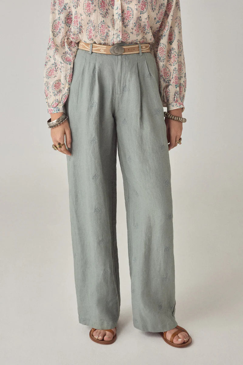 Person wearing a floral blouse and light gray wide-leg pants on a plain background