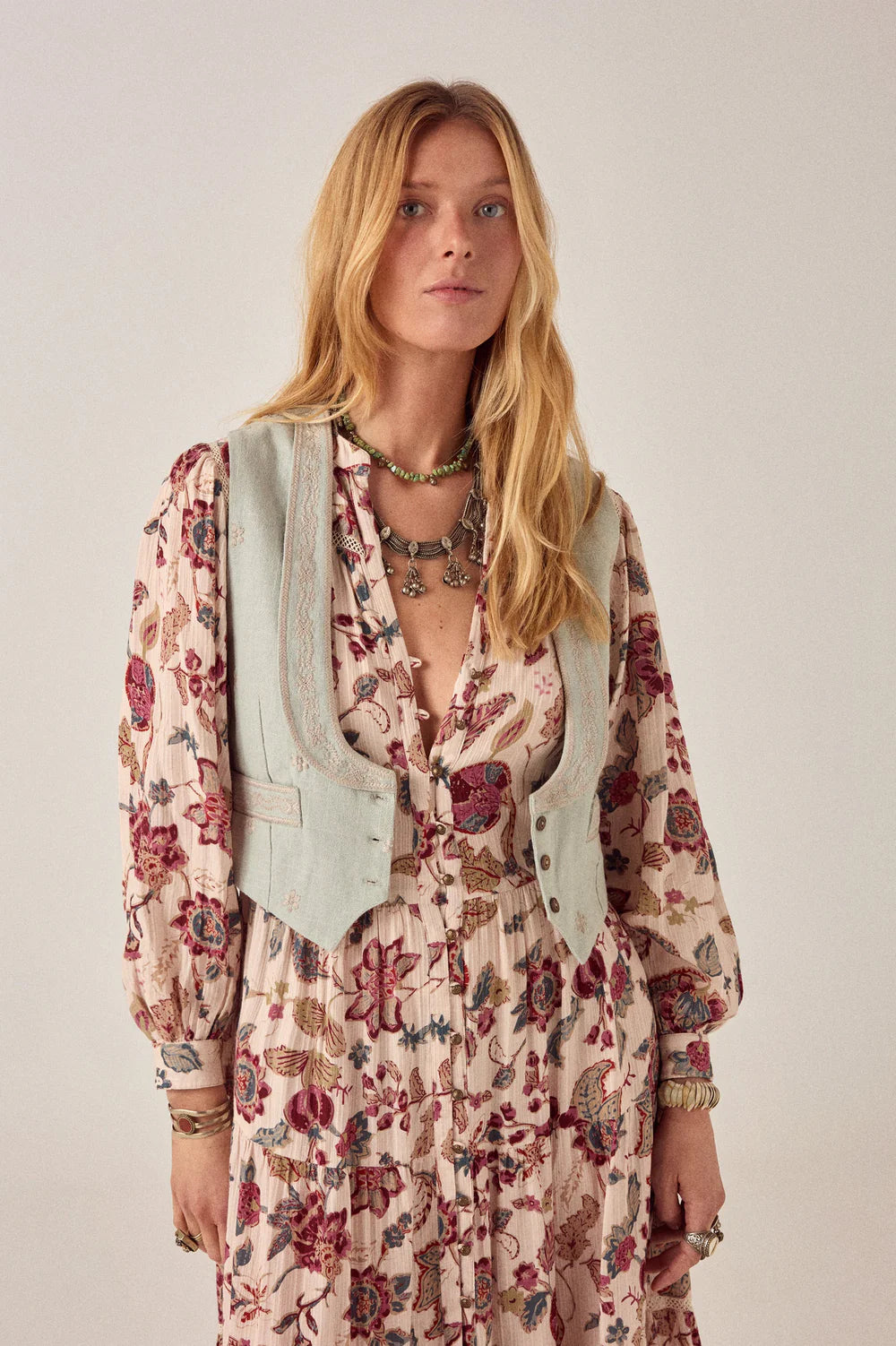 Woman wearing a floral dress with a light blue cardigan on a plain background