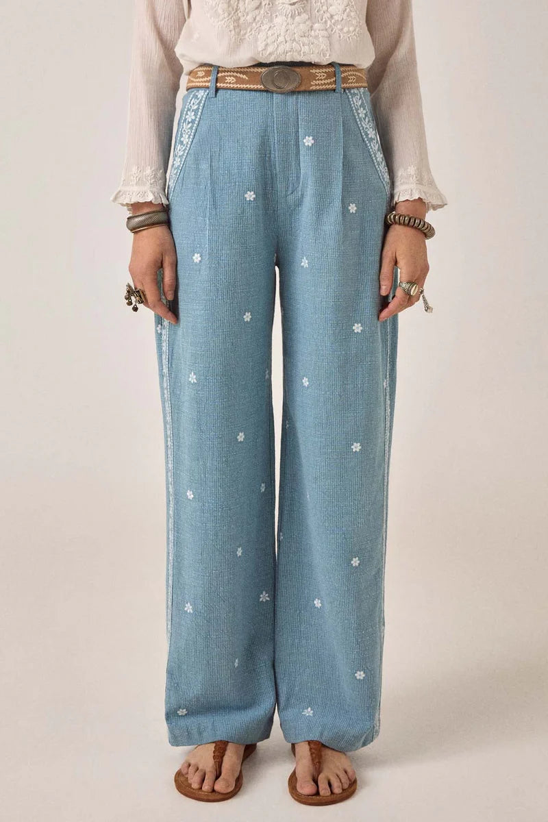 Person wearing light blue denim pants with white floral patterns on a plain background. Western bottoms, western trousers, western pants 