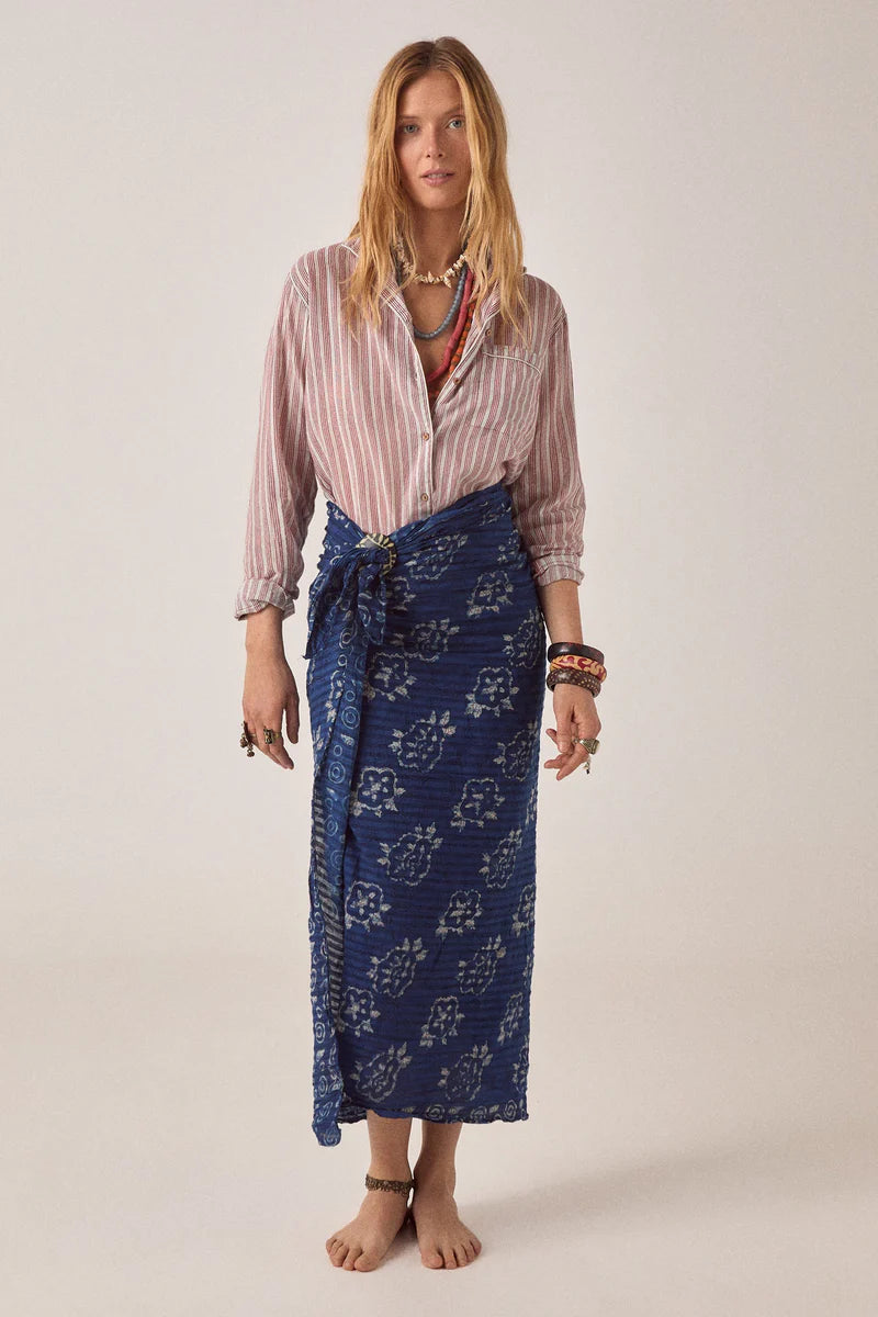 Woman wearing a striped shirt and blue patterned skirt on a plain background