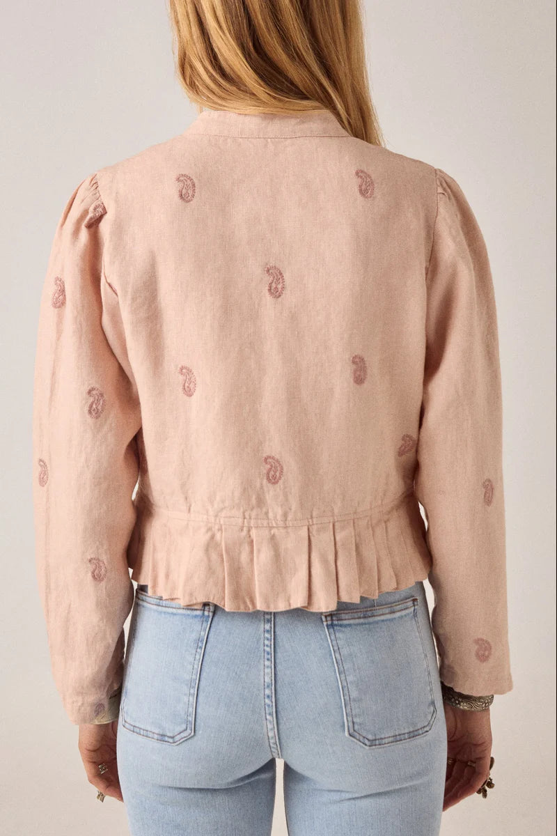 Pink embroidered jacket worn by a person on a plain background