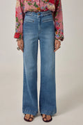 Person wearing blue jeans and a colorful floral blouse on a plain background