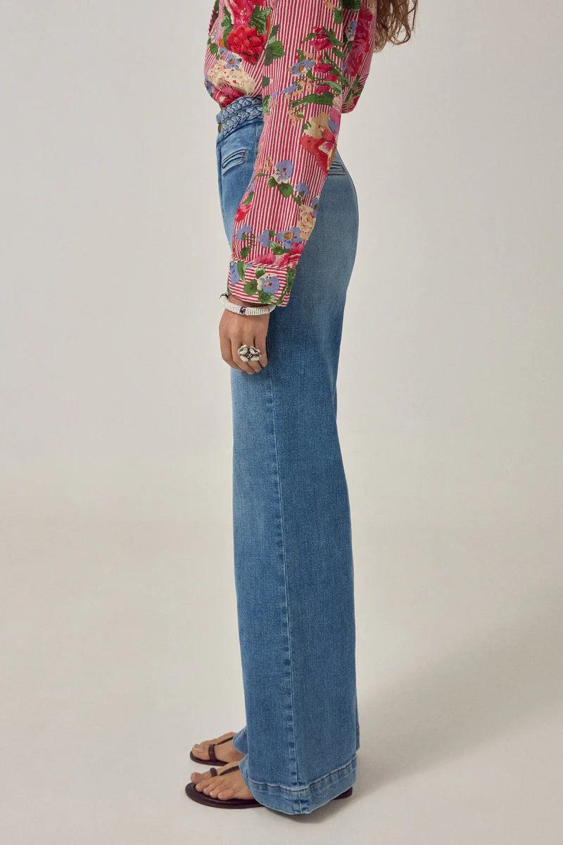 Person wearing a floral blouse and blue jeans on a plain background