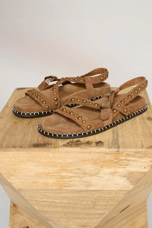 Brown sandals with stud details on a wooden block