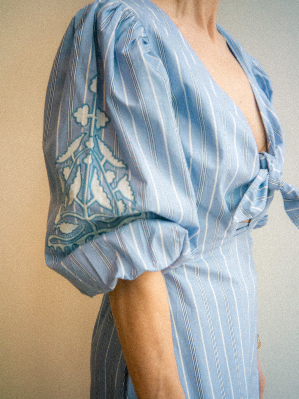 Light blue dress with white stripes and intricate patterns on a neutral background