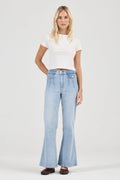 Woman wearing light blue flared jeans and a white top on a white background