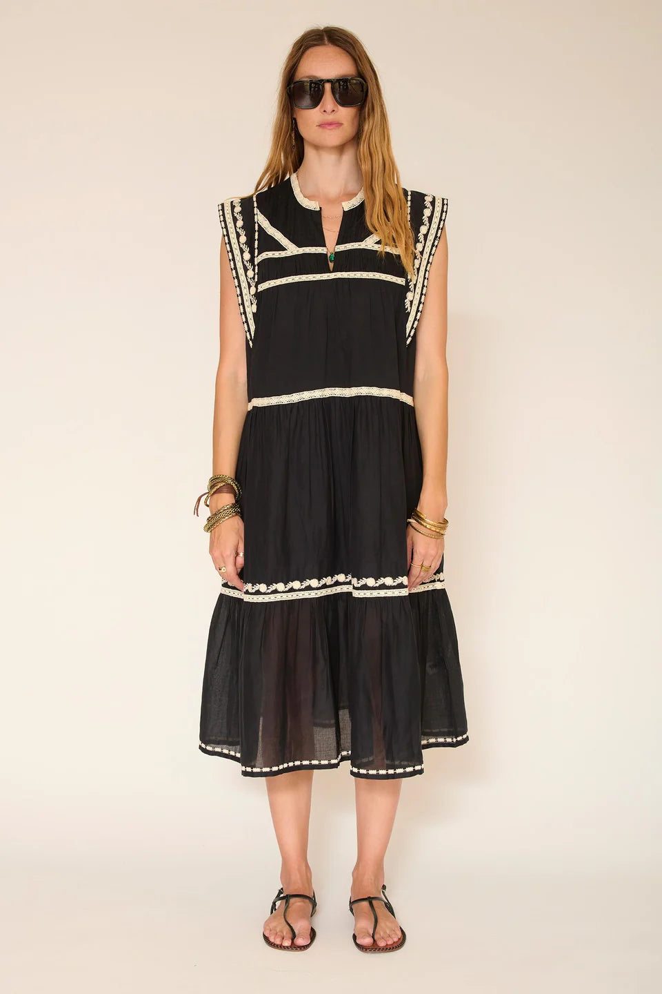 Woman wearing a black dress with white trim against a beige background