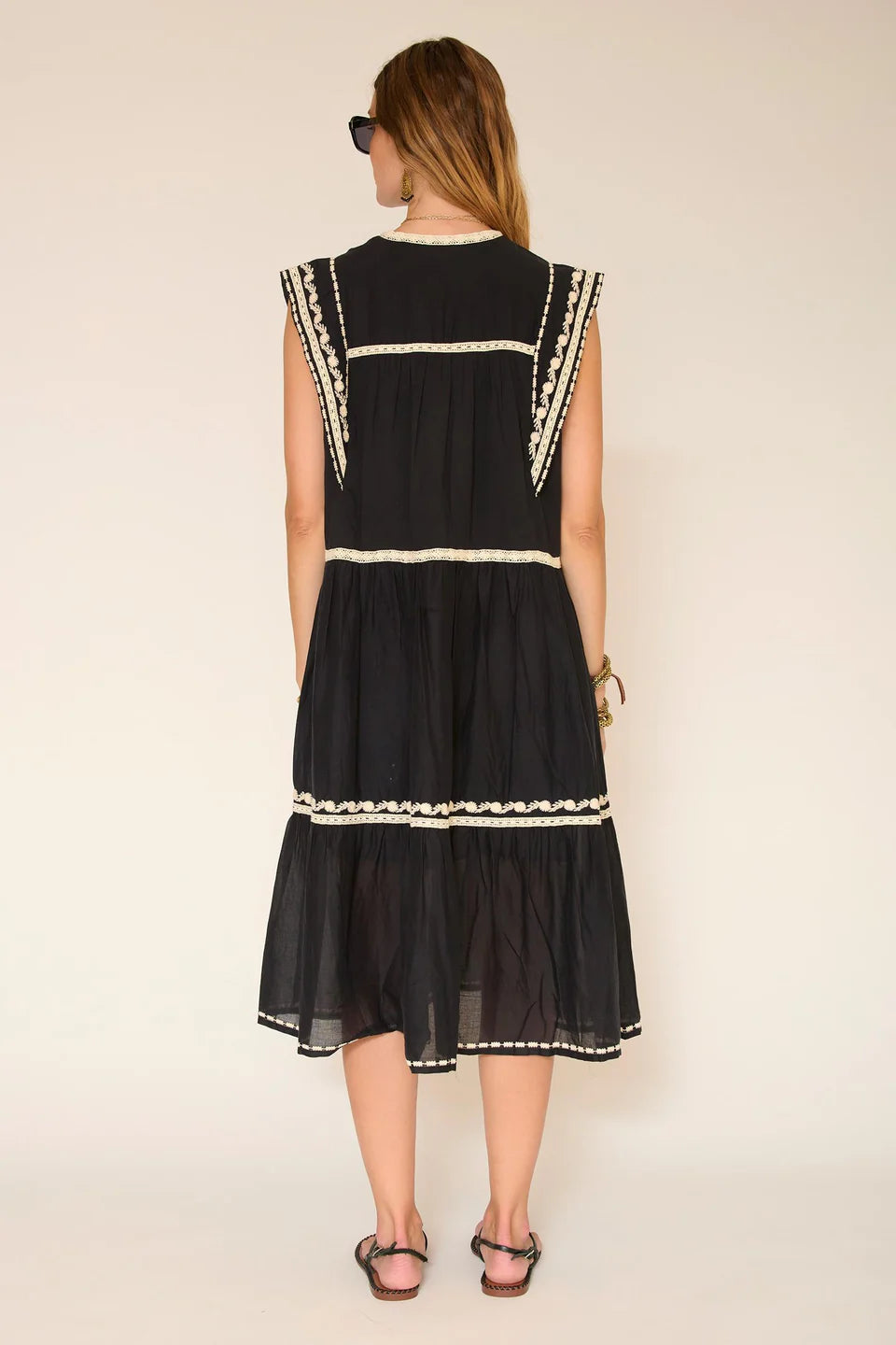 Black dress with white lace details worn by a person on a plain background