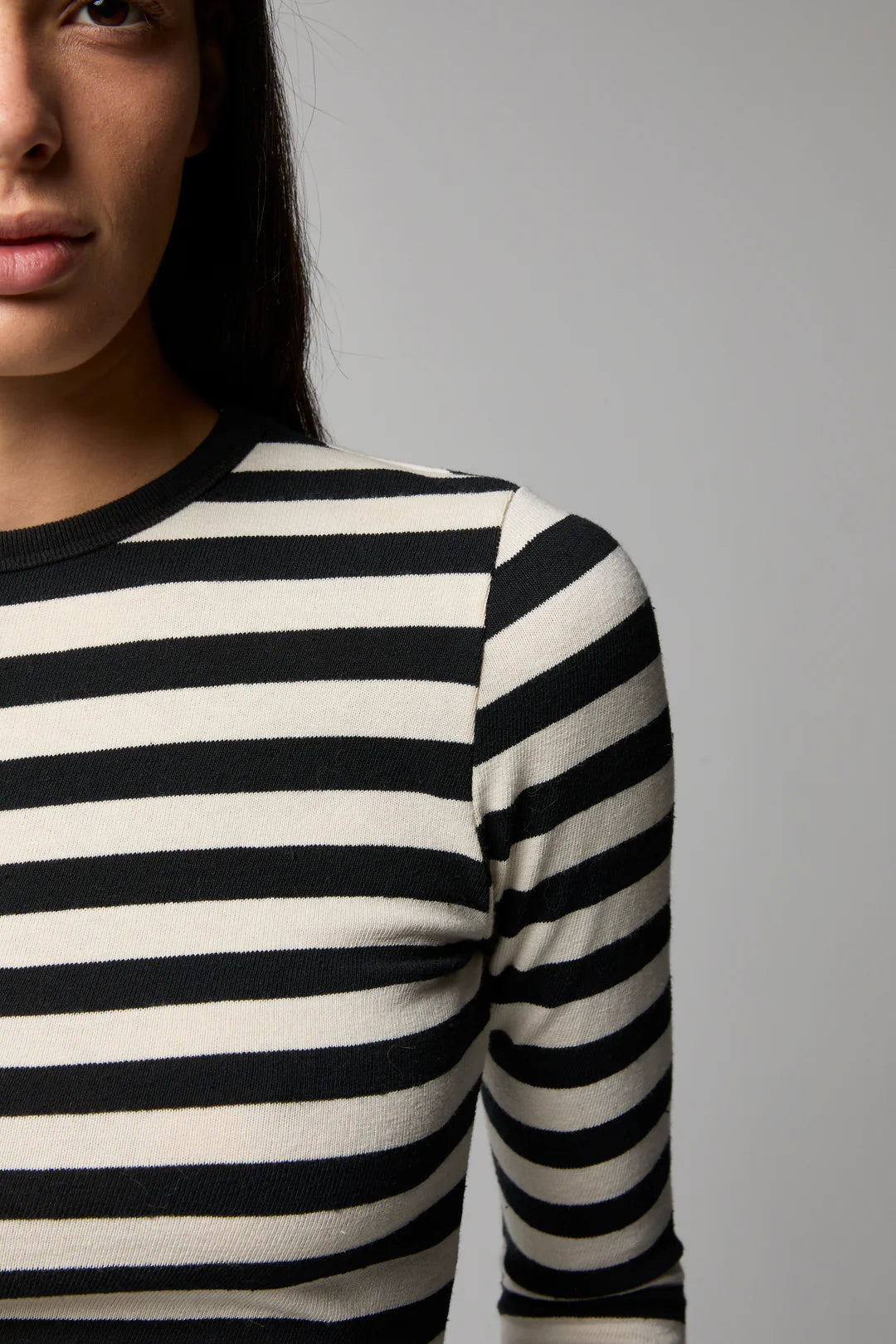 Person wearing a black and white striped long-sleeve shirt against a gray background