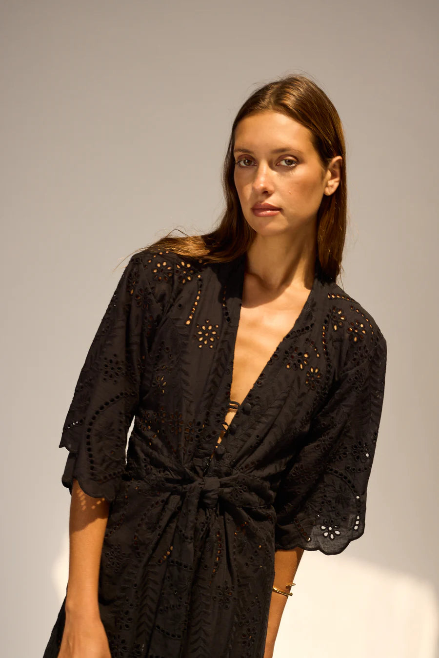 Woman wearing a black lace dress against a plain background