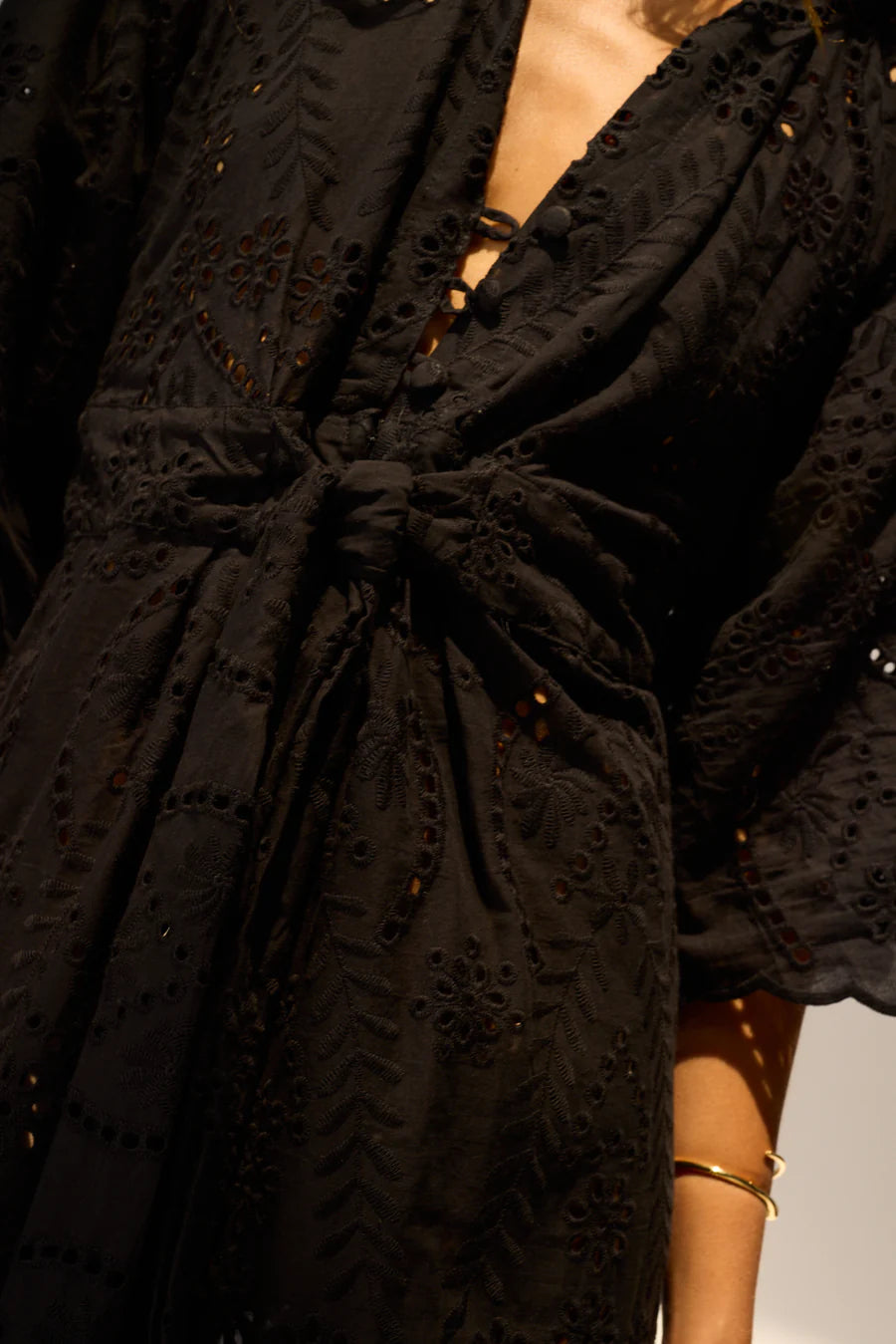 Black embroidered dress with a tie detail on a plain background