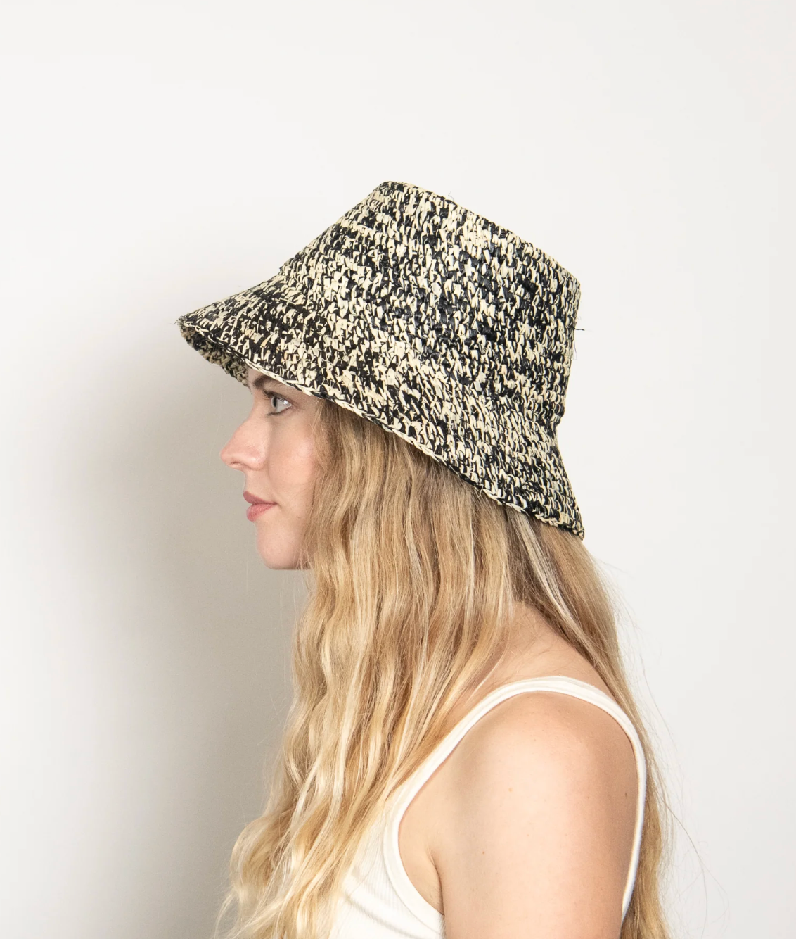 Woman wearing a patterned RAFFIA bucket hat against a plain background