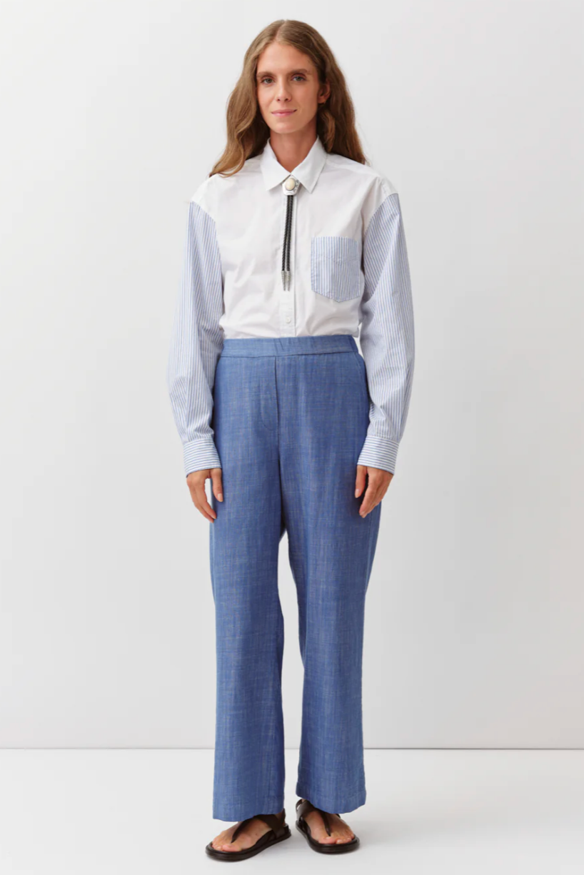Woman wearing a light blue shirt and blue pants on a white background
