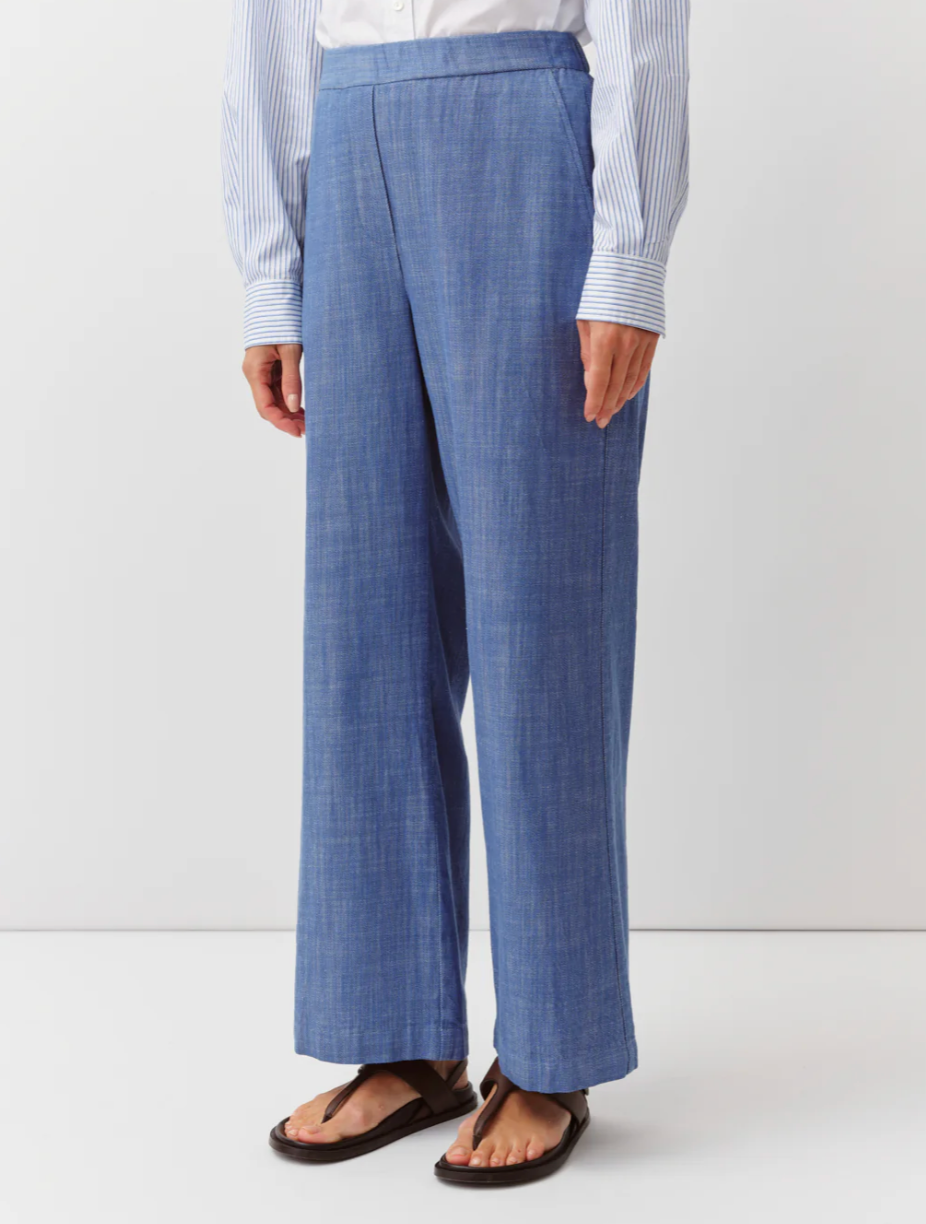 Person wearing blue checkered pants and a striped shirt on a white background
