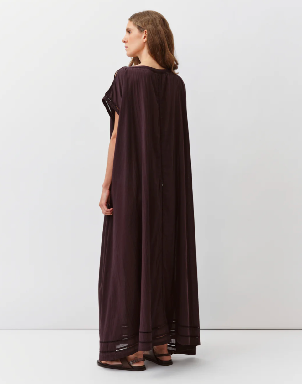 Woman wearing a long dark brown dress on a white background