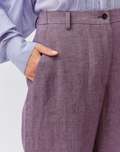 Close-up of a person wearing purple textured pants with a light background