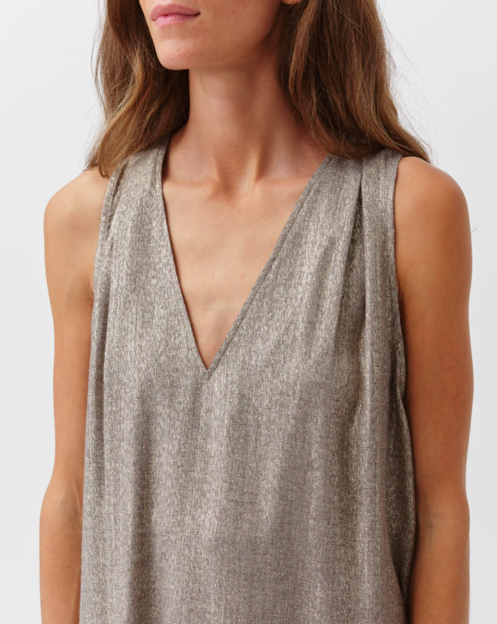 Woman wearing a sleeveless metallic top against a white background