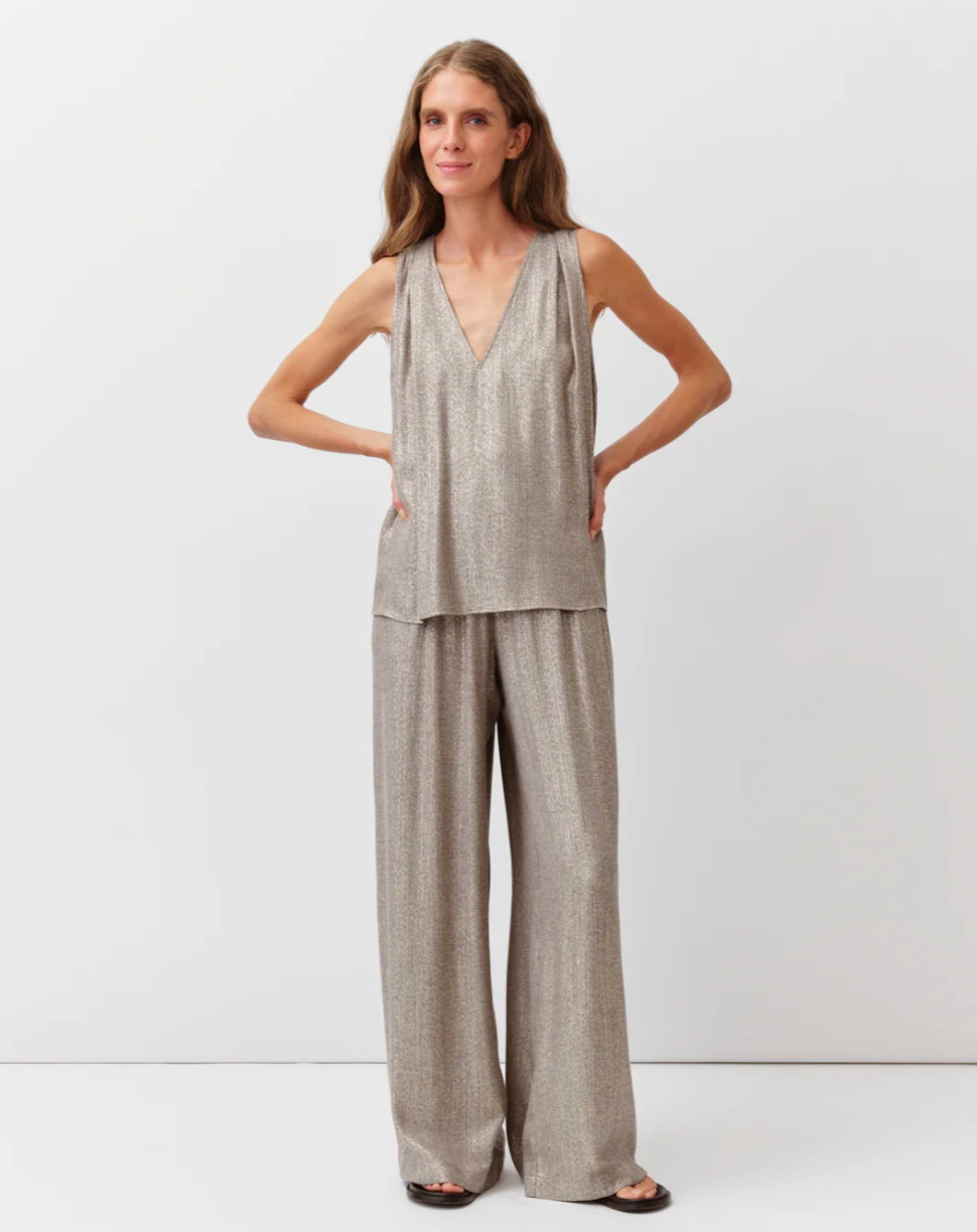 Woman wearing a gray sleeveless top and wide-leg pants on a white background