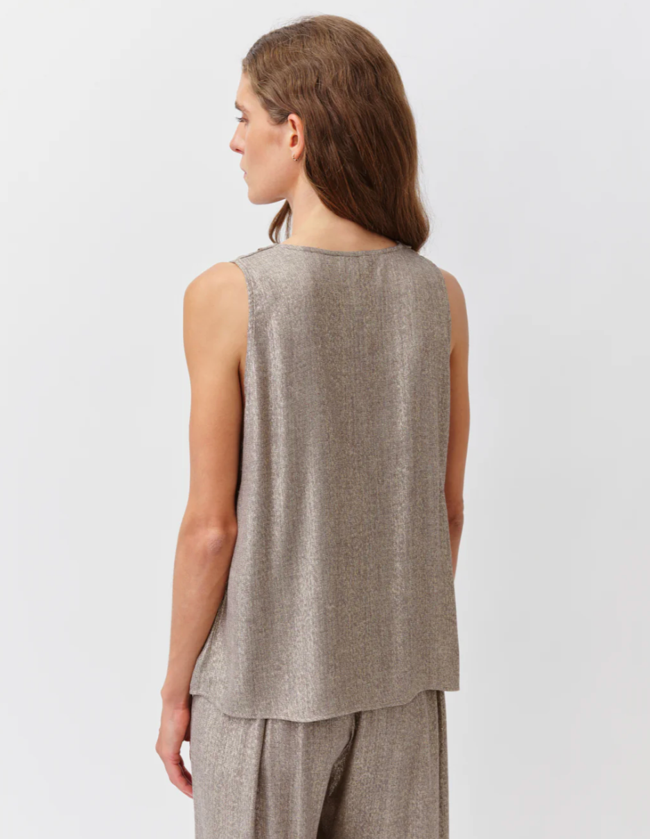 Woman wearing a sleeveless beige top and pants on a white background