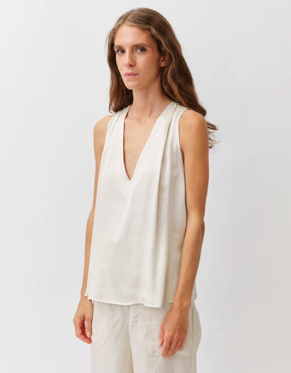Woman wearing a white sleeveless top with a plain background
