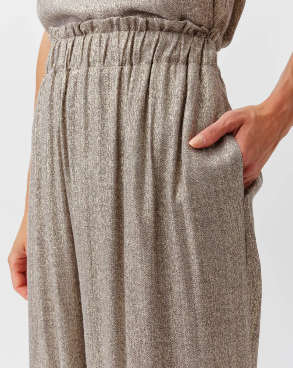 Close-up of a person wearing brown pants with a plain background