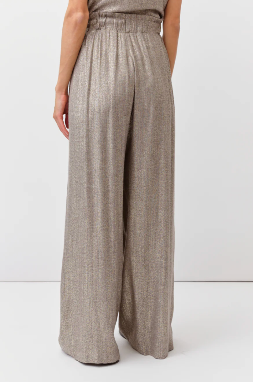 Person wearing beige wide-leg pants on a white background