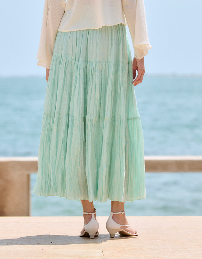 Person wearing a light green skirt with a blurred ocean background